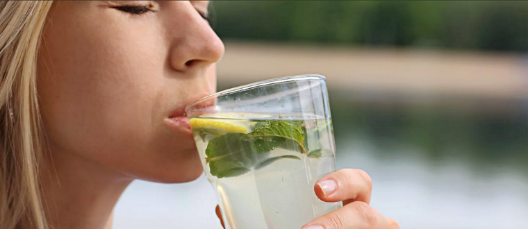Женщина пьет лимонную воду для похудения
